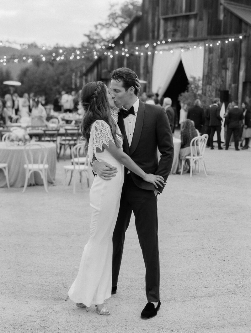 stone cold fox white jumper with lace sleeves wron by bride as he kisses her husband at greengate ranch and vineyard in san luis obispo, ca