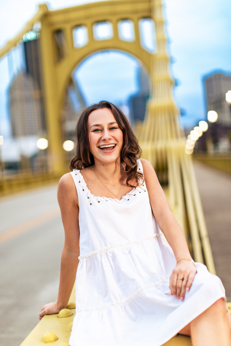 This brown hair laughing girl stands on the Roberto Clemente bridge in Pittsburgh Pennsylvania.