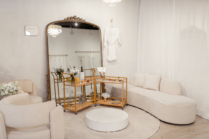 Bridal Bliss Experience setup in front of a large mirror and stage at our semi private lounge. Bridal robe, and a cart with sweets and champagne.  