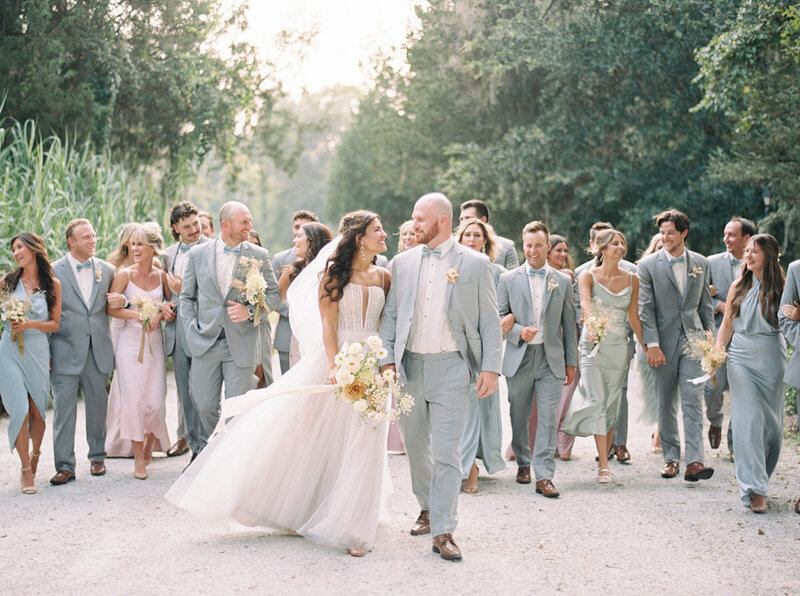 Bride and groom kissing while bridal party cheers around them