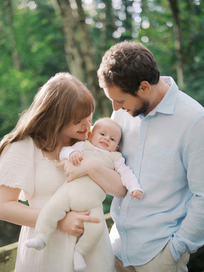 Mom and dad snuggling their newborn son in a forest in Squamish