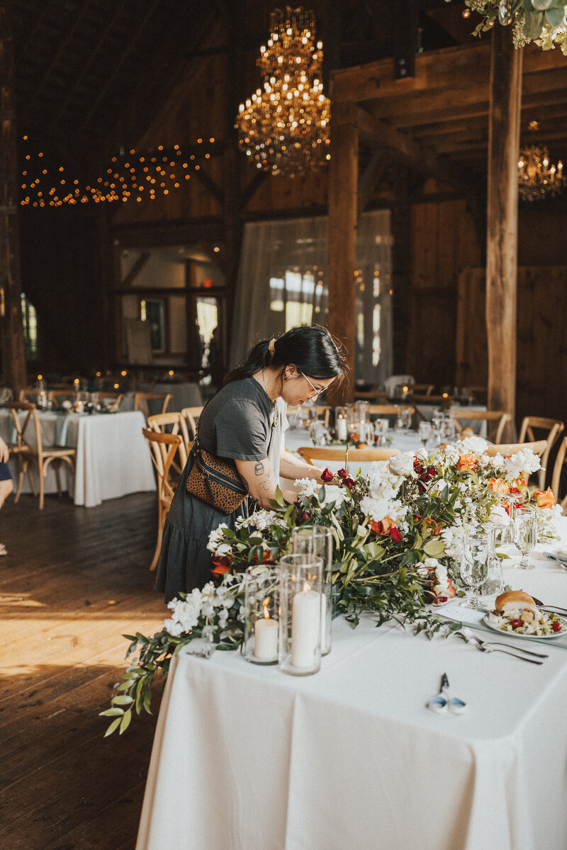 woman setting up a table with flowers and candles on it
