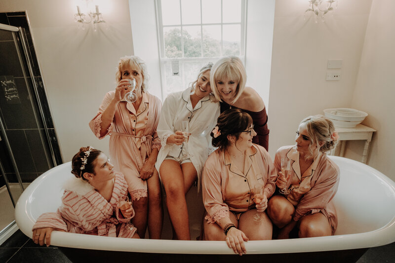 bride and bridal party in silk gowns sitting in bath drinking champagne fun alternative wedding photographer scotland