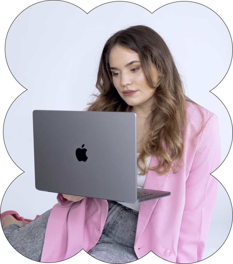 Founder in a pink blazer sitting on the floor and looking at her laptop