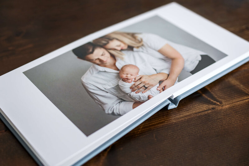 leather album laid open to a photo of parents holding their  newborn  baby
