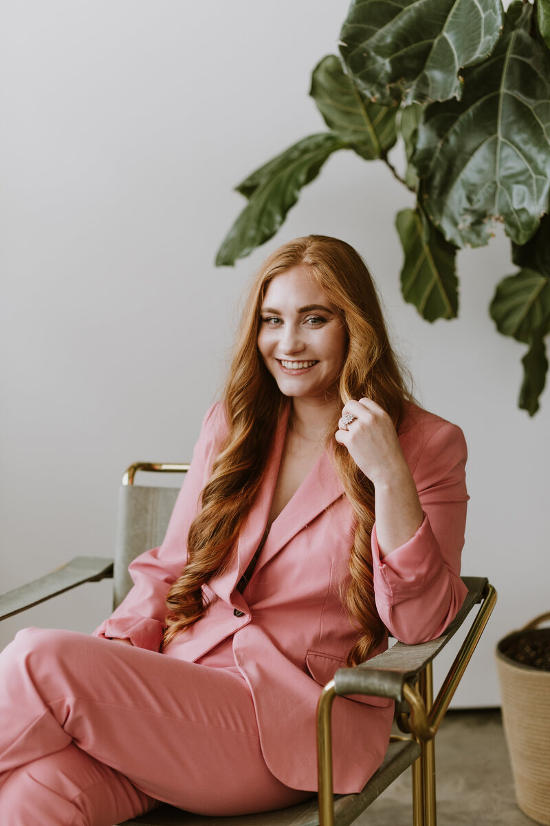 Lead coordinator Cassi Hoven seated in a chair with green leaves behind her and a white background