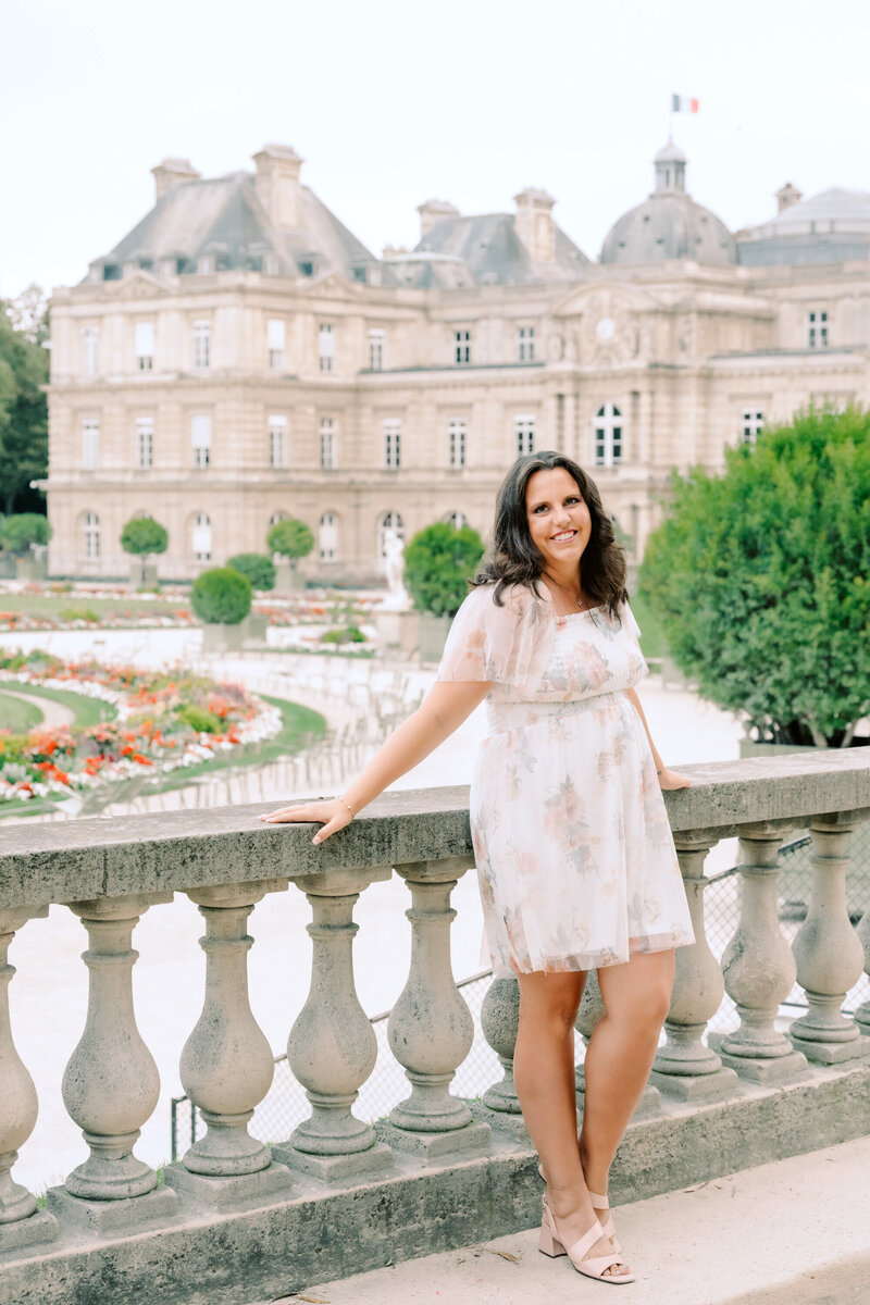 A woman in a blue dress standing in front of the eiffel tower.