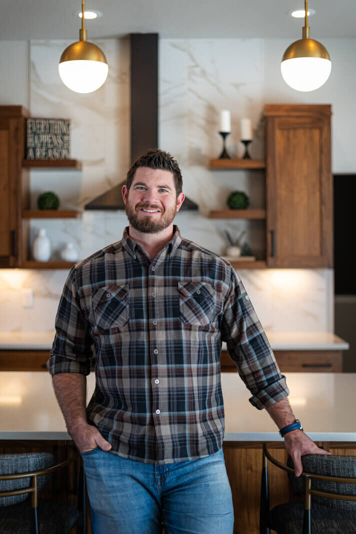 man with plaid shirt smiling in a kitchen