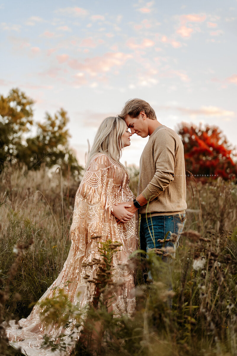 Newborn baby wrapped in soft blue fabric, yawning while wearing a matching knit bonnet. Captured by Honeywild Photo, a Grand Rapids newborn photographer specializing in artistic and timeless baby portraits