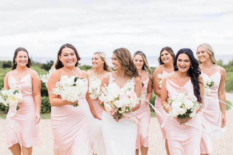 bride and bridesmaids laughing and holding their bouquets