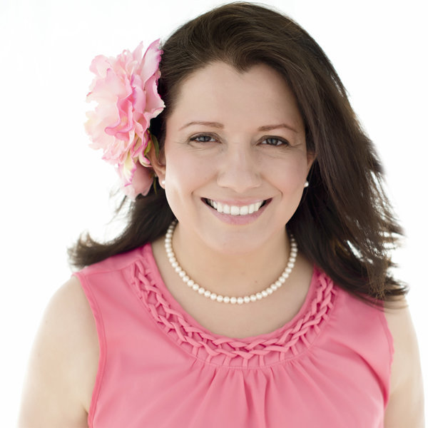 personal branding Portrait  headshot of  mother smiling looking at the camera  with  flowers in her hair and wearing a pink color  braided top  and  beautiful white pearl  necklace