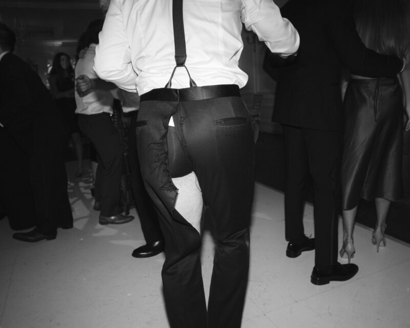 Black and white image of groomsman's ripped pants on the dance floor