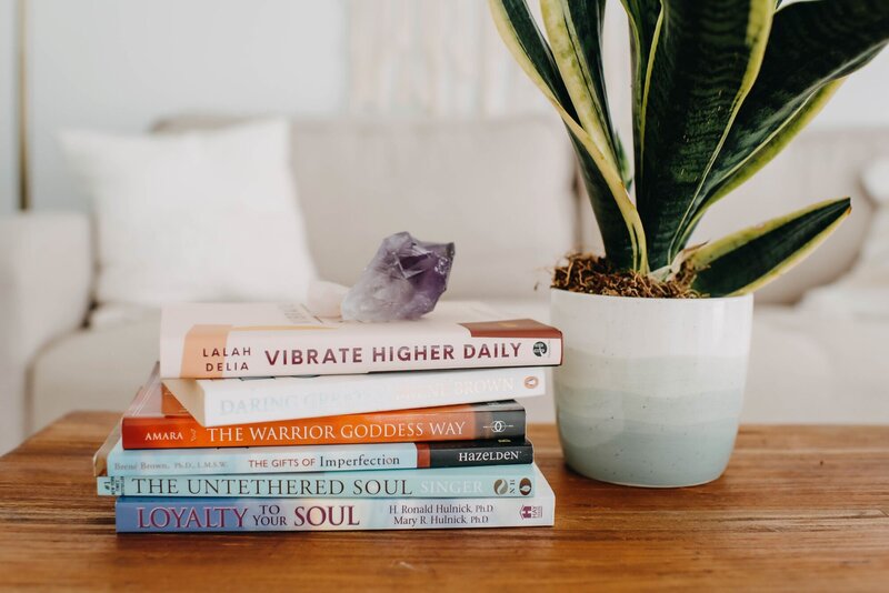 stack-of-healing-books-next-to-plant-on-table