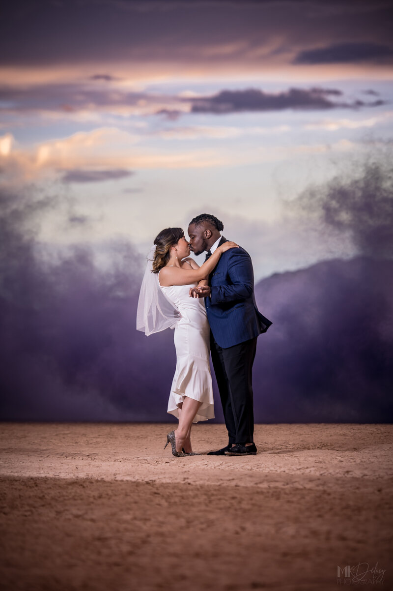Bride and groom sharing a kiss surrounded by colorful smoke at sunset, romantic elopement portrait in Lincoln, Nebraska by Legacy in Light Photography.