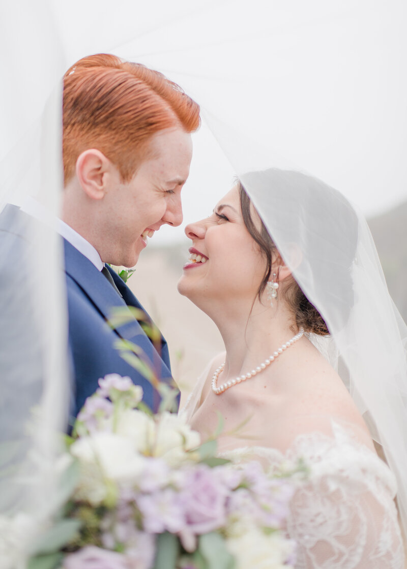 wedding couple under veil at their foggy monterey beach wedding