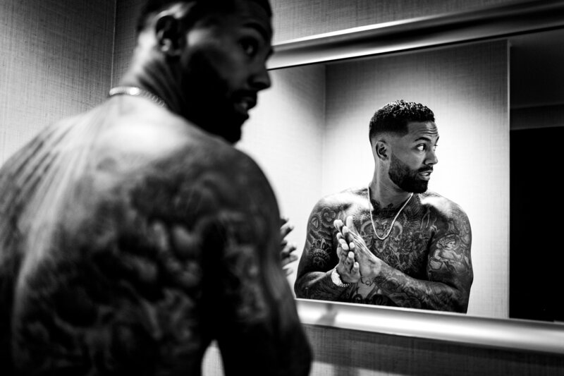 A shirtless groom with many tattoosgetting ready in front of a mirror at the Renaissance Hotel in Toledo Ohio 