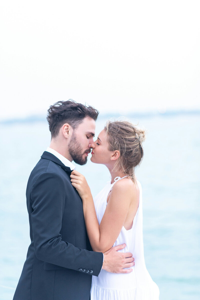 couple kissing on the deck of a yacht, with the ocean in the background