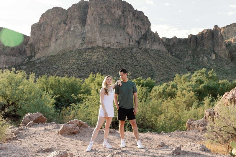 Woman leans on fiance's shoulder in the desert mountains 