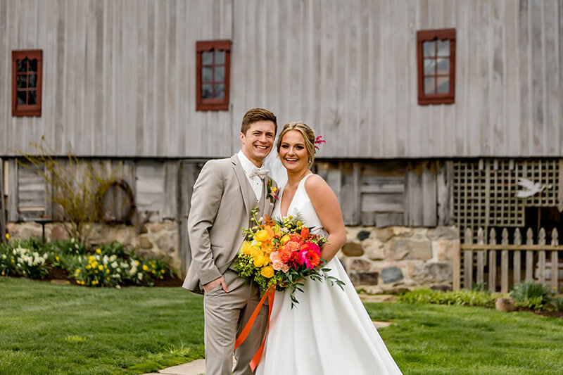 A bride and groom in front of the Country Strong barn.