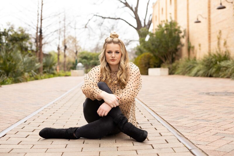 bright light and airy girl sitting on a brick walkway