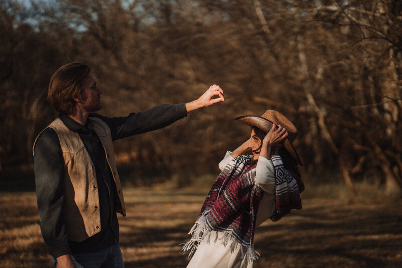 A man reaches for his cowboy hat as his bride ducks out of his reach.