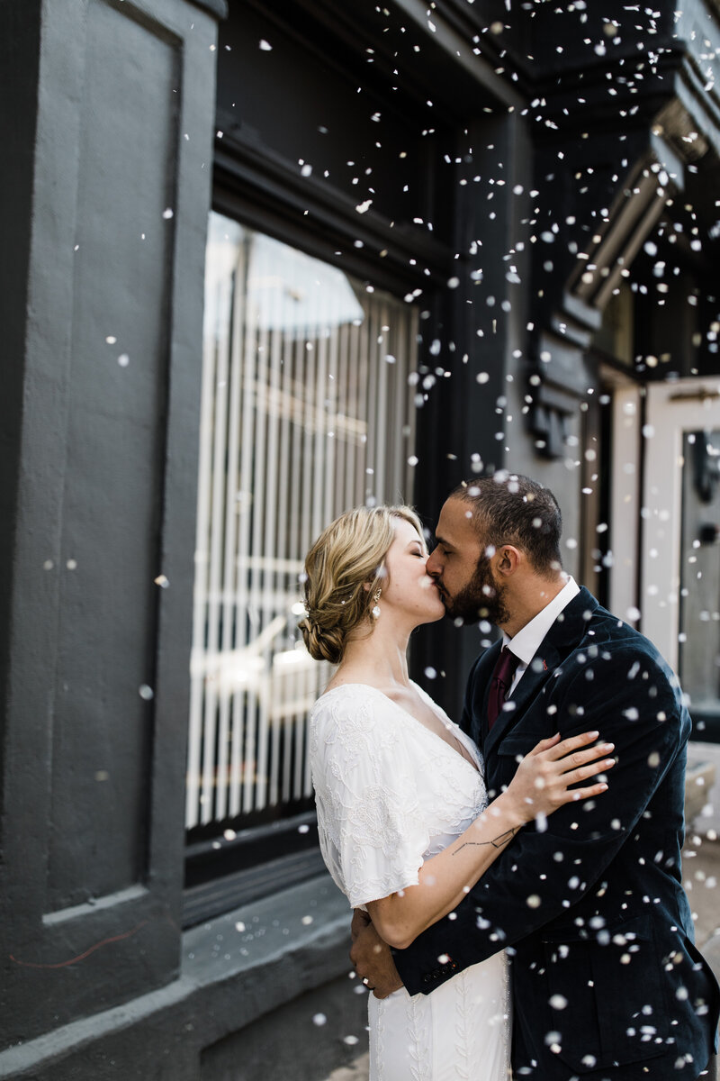 Bride and groom kissing while confetti falls around them