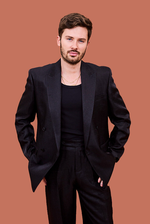 Jordan wearing a black double-breasted blazer, matching trousers, and layered gold necklaces, styled in a professional Sydney hair salon.