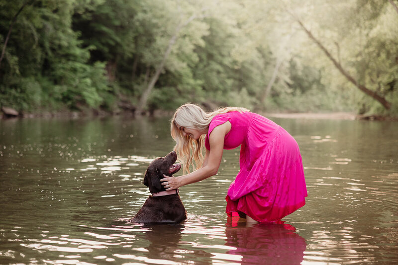 Woman and her dog in a river looking at each other during sunset in Bonne Terre, Missouri. 