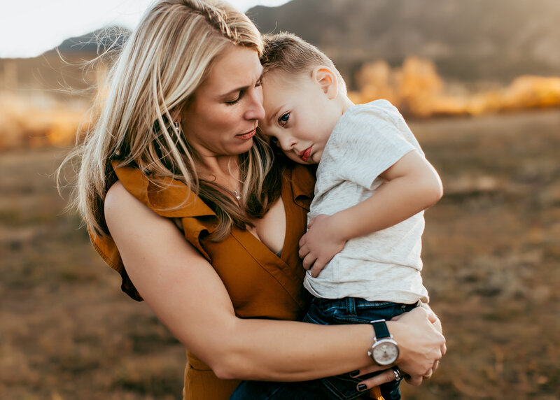 Mother comforts son during family photography session with Erin JAchimiak Photography in the foothills of Colorado at sunset