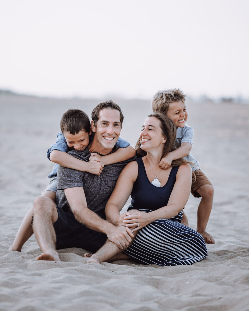 A family hanging out in the sand at the beach.