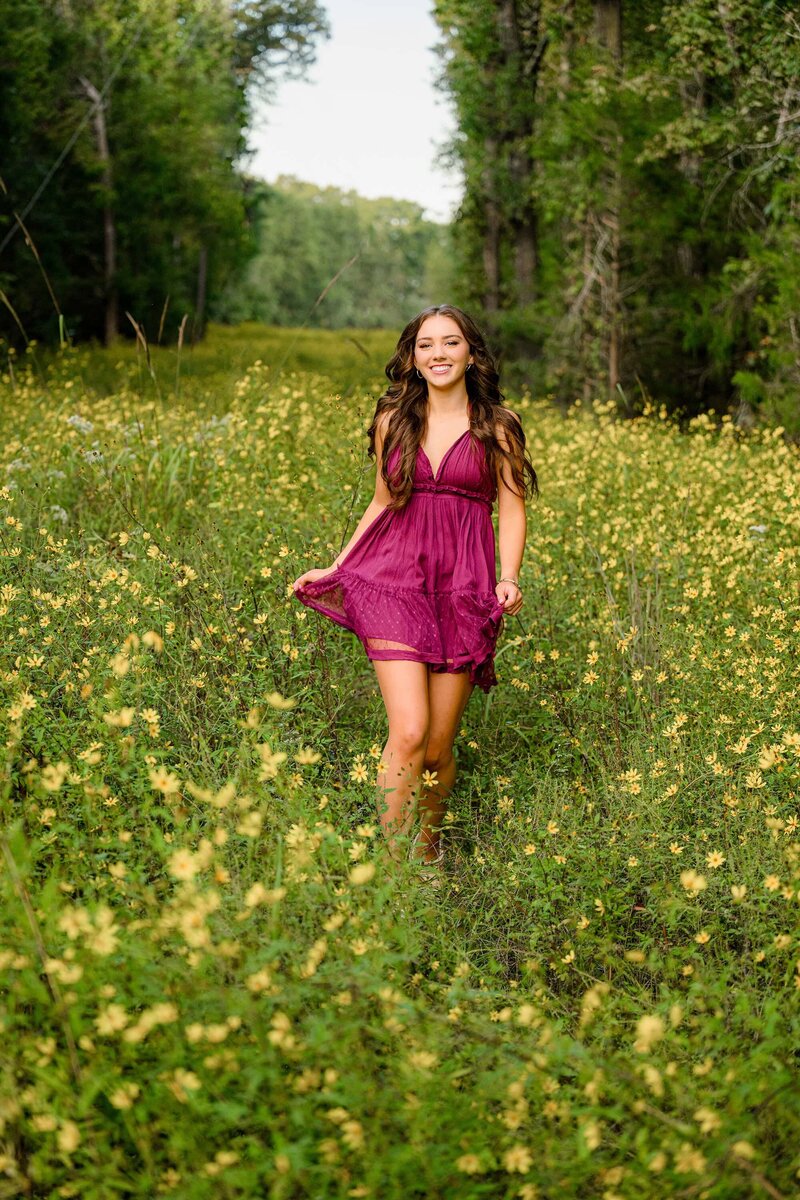 senior running through a field of yellow flowers