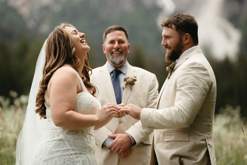 Elopement Ceremony Ideas | Bride tosses her head back and laughs while during her elopement ceremony, groom and officiant have big smiles.