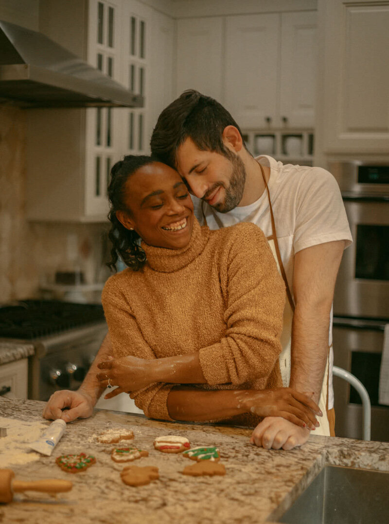 A person standing behind their partner as they make cookies.