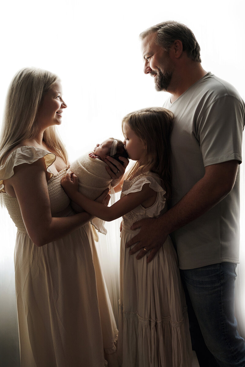 Backlit image of the sweetest family holding their newborn baby girl