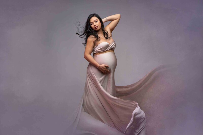 Pregnant Tacoma Latina mom poses in flowing pink strapless gown with hair and fabric flowing in wind.