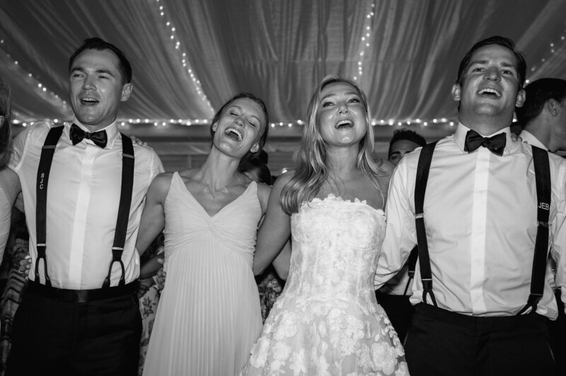 Bride and groom with loved ones singing and embracing at their wedding reception in New York -  by Daniella Diaz Photo