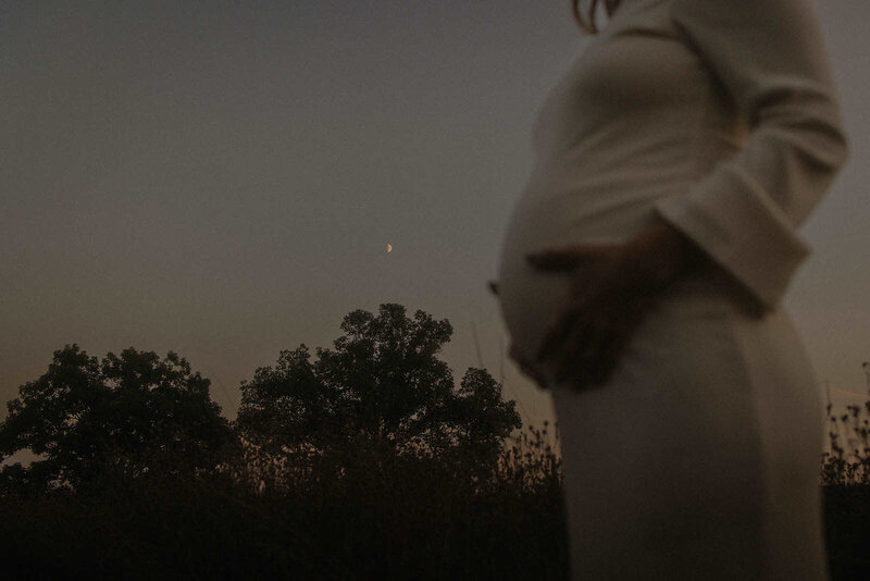 A woman holding her pregnant belly during a maternity shoot at dusk in Boston