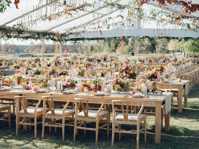 Eye-catching oversized chuppah overflowing with fall florals featuring dahlias, garden roses, rain tree pods, and fall greenery. Autumnal hues of terra cotta, dusty pink, copper, and yellow create this statement wedding piece. Designed by Rosemary and Finch in Nashville, TN.