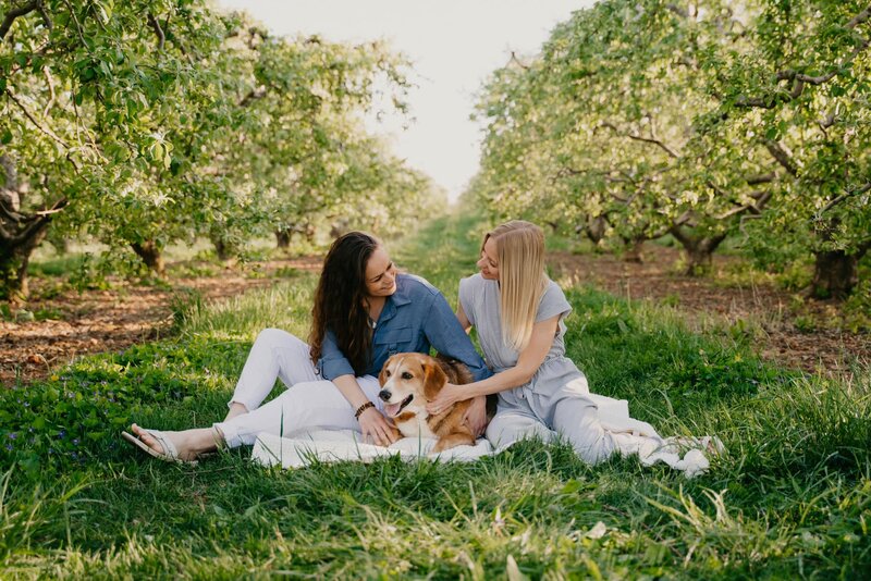 a family photo of two girls and their dog in an orchard
