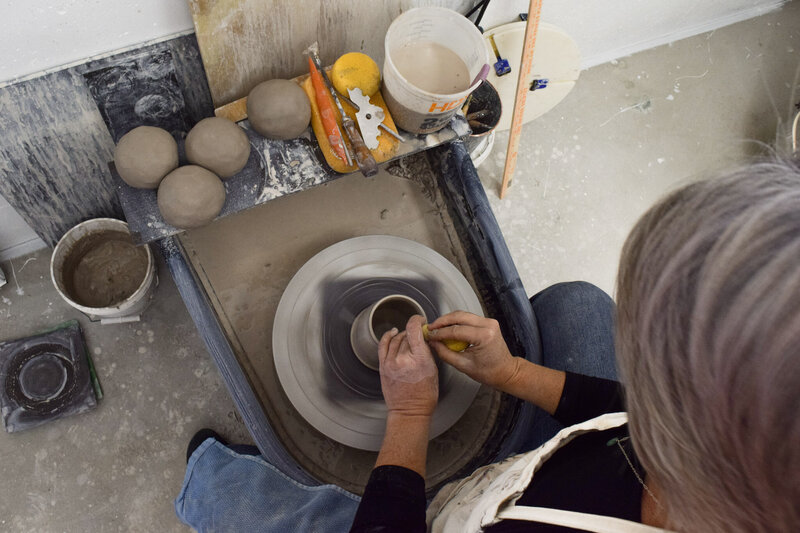 Measured clay balls sit beside a pottery wheel, waiting to be thrown and turned into handmade pottery