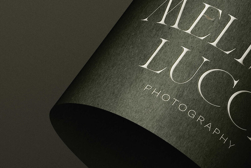 A close-up of a dark, textured paper with the words "MELI LUCC PHOTOGRAPHY" printed in elegant white serif font, perfect for showcasing brand and web design for small businesses by a skilled Showit designer.