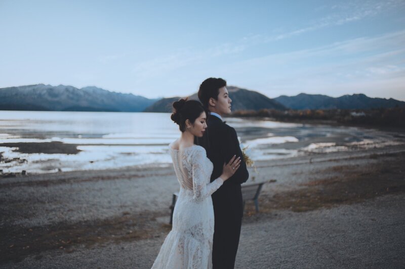 A bride and groom together at the lakeside.