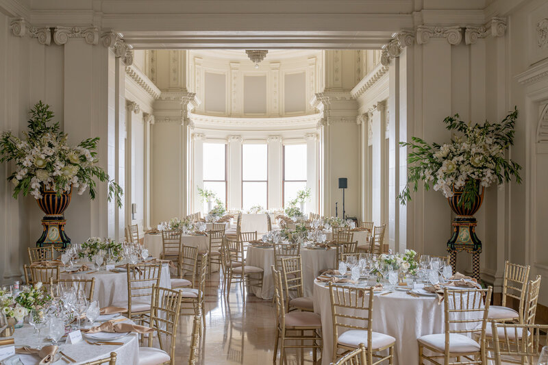 San Francisco wedding photographer documents luxury reception at Flood Mansion with gold Chiavari chairs and elegant white linens in classical ballroom