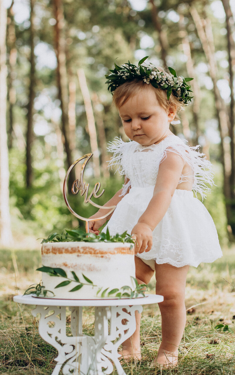 Petite fille en forêt derrière un gateau d'anniversaire.  Mise en scène imaginée dans le cadre de l'organisation d'événements pour particuliers.