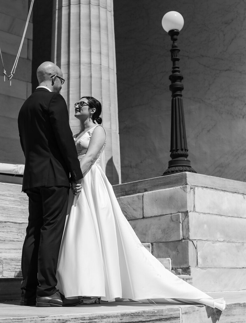 Bride and groom hold hands on the steps of the Erie Art Museum