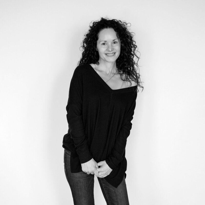 Black and white portrait of a smiling woman in a casual sweater.