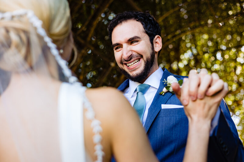Wedding couple holding hands and smiling during a first look in Ann Arbor Michigan. Lots of emotion and tears