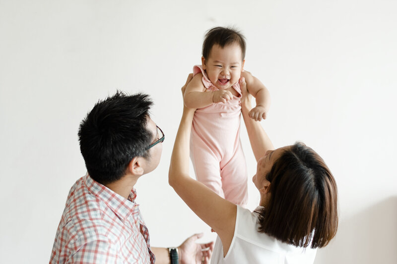 Asian family holding up their smiling baby