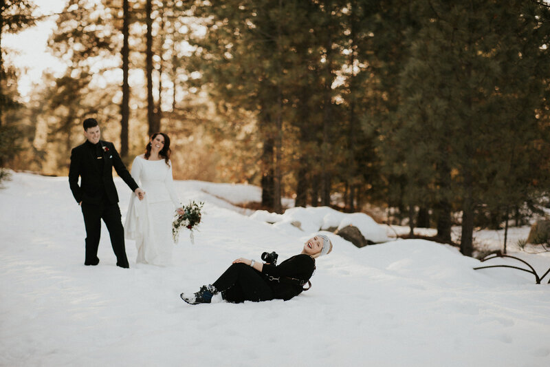 Photographer falling in the snow while taking a photo of wedding couple