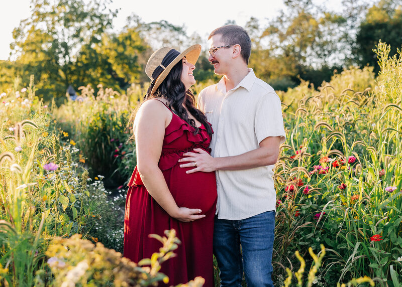 Candid lifestyle maternity portrait of a couple in a field of wildflowers.